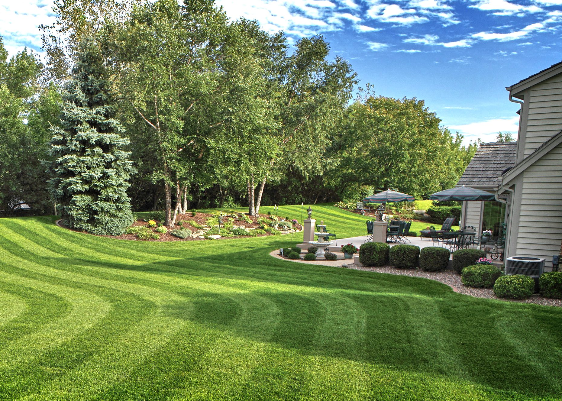 Backyard lawn with sweeping curved mowing stripes and a patio