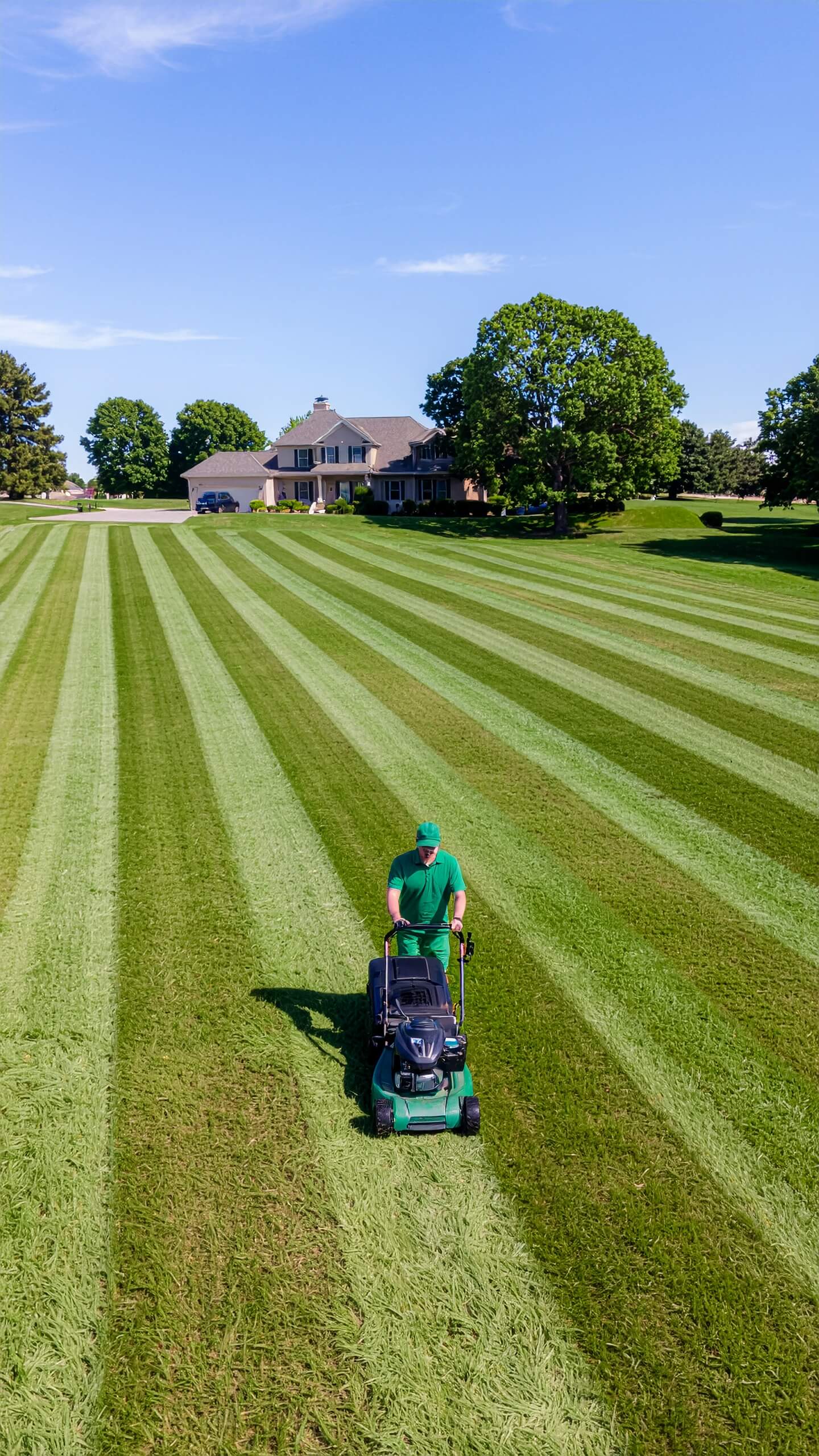 Mojica crew member mowing perfect stripes into a large green lawn